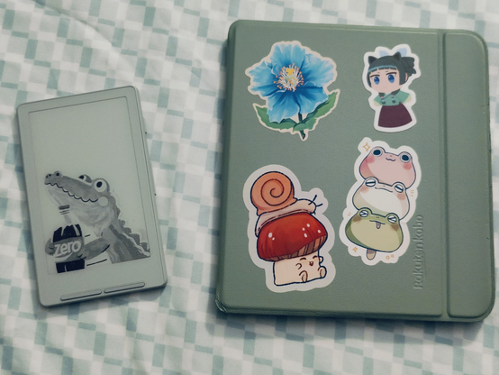 The Xteink X4 and the Kobo Libra Colour. The Xteink has a cartoon crocodile holding a coke as a sleep image. The Kobo has stickers on the sleep cover.